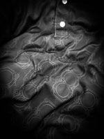 black polo shirt featuring a subtle 3S-GTE engine head gasket all over graphic.