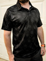 Black polo shirt for car enthusiasts featuring an all-over, minimalist turbocharger pattern.
